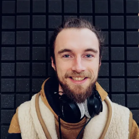 Julien Wegner, webdesigner, souriant, un casque audio autour du cou